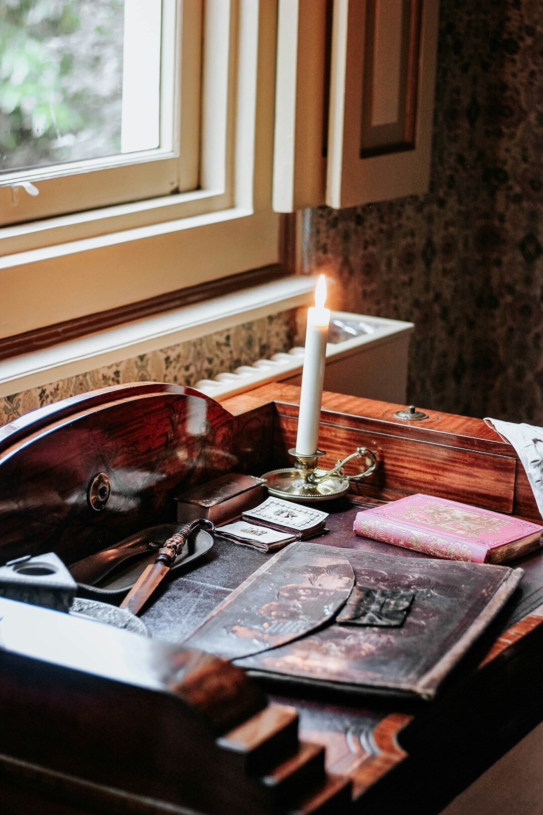 Vintage wooden writing desk with a typewriter, ink pen, papers and a lit candle